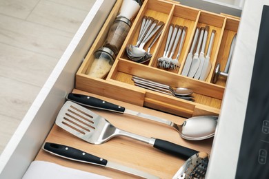 Photo of Box with cutlery in drawer, closeup. Kitchen utensils storage