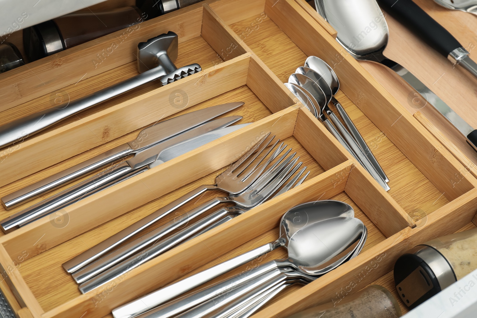 Photo of Cutlery in wooden box, closeup. Kitchen utensils storage