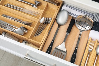 Photo of Box with cutlery in drawer, closeup. Kitchen utensils storage