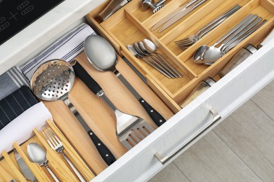 Photo of Box with cutlery in drawer, closeup. Kitchen utensils storage