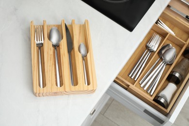 Photo of Set of cutlery on counter and other utensils in kitchen drawer