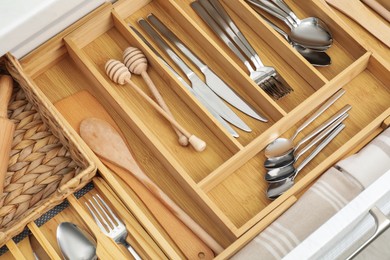 Photo of Box with cutlery in drawer, closeup. Kitchen utensils storage