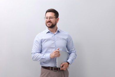 Portrait of smiling businessman with laptop on grey background