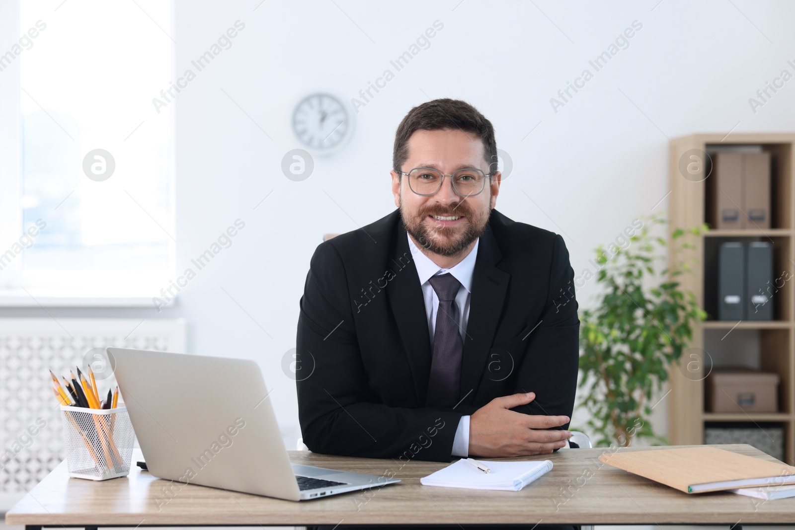 Photo of Portrait of smiling businessman at table in office