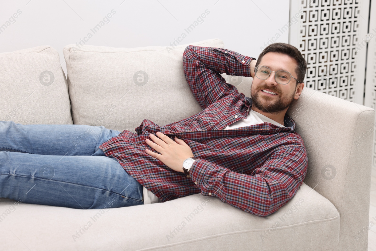 Photo of Smiling man relaxing on sofa at home