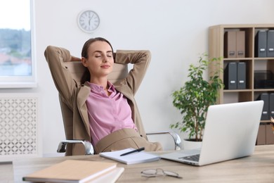 Photo of Businesswoman with hands behind her head relaxing at table in office. Break time