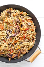 Photo of Stir-fry noodles with sea food and vegetables in wok on white wooden table, top view