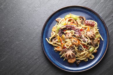 Photo of Stir-fry noodles with sea food and vegetables on dark textured table, top view. Space for text