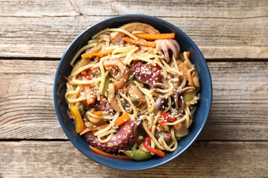 Photo of Stir-fry noodles with sea food and vegetables on wooden table, top view