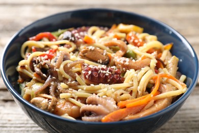 Photo of Stir-fry noodles with sea food and vegetables on wooden table, closeup