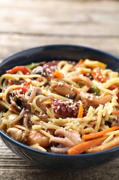 Photo of Stir-fry noodles with sea food and vegetables on wooden table, closeup