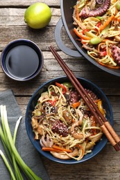 Photo of Stir-fry noodles with sea food and vegetables served on wooden table, flat lay