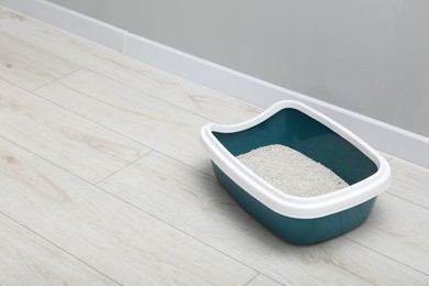 Cat tray with clumping litter on floor indoors, space for text