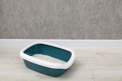 Photo of Cat tray with clumping litter on floor indoors, space for text