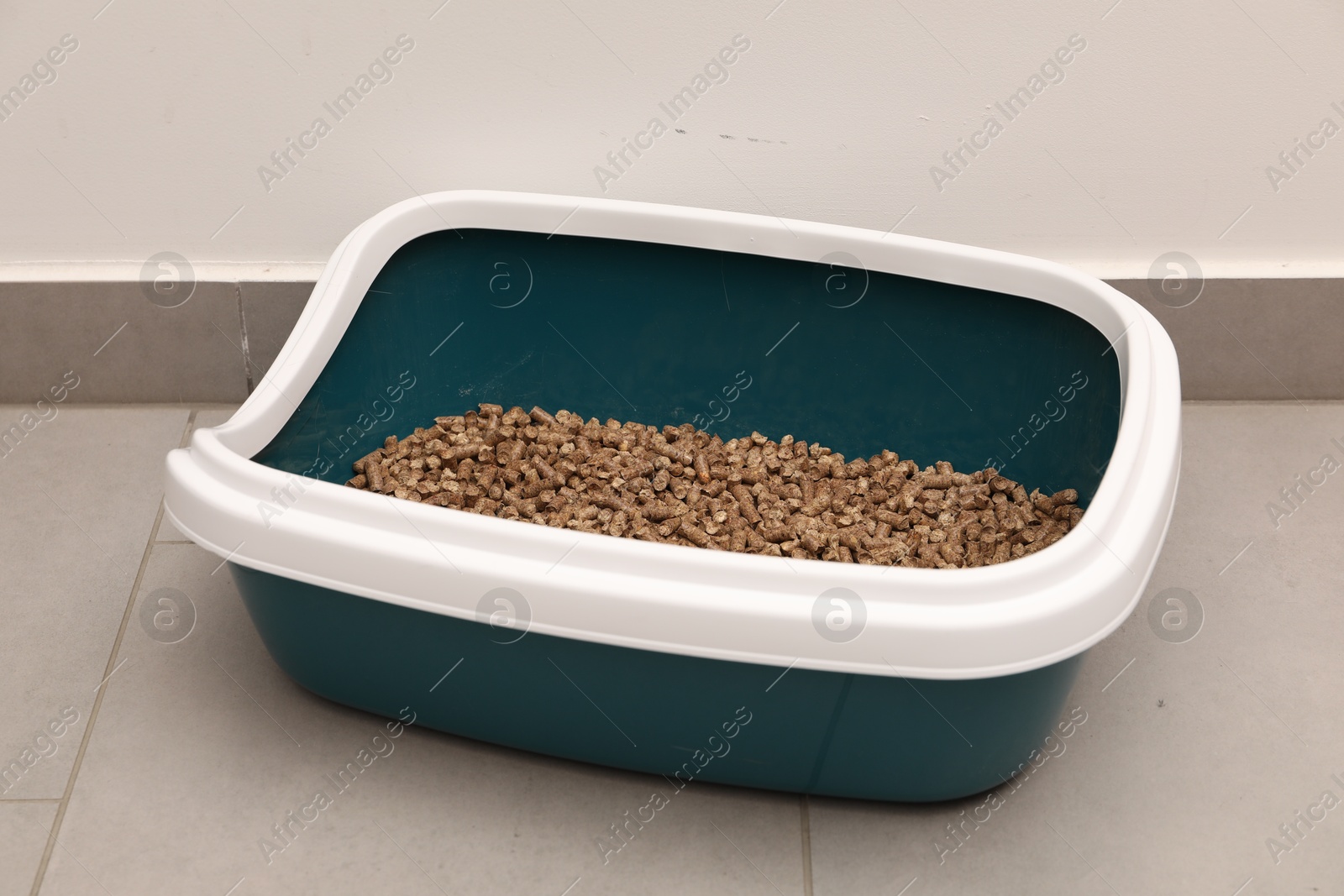 Photo of Cat litter tray with filler on floor indoors