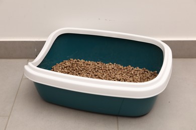 Photo of Cat litter tray with filler on floor indoors