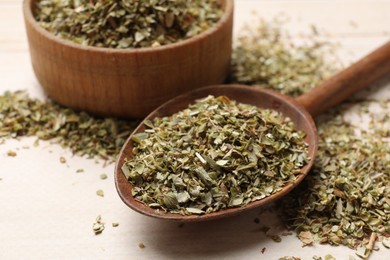 Photo of Dried oregano in wooden spoon on table, closeup