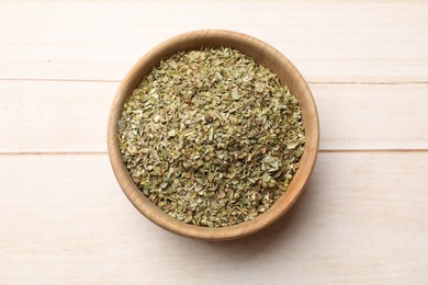 Photo of Dried oregano in bowl on wooden table, top view