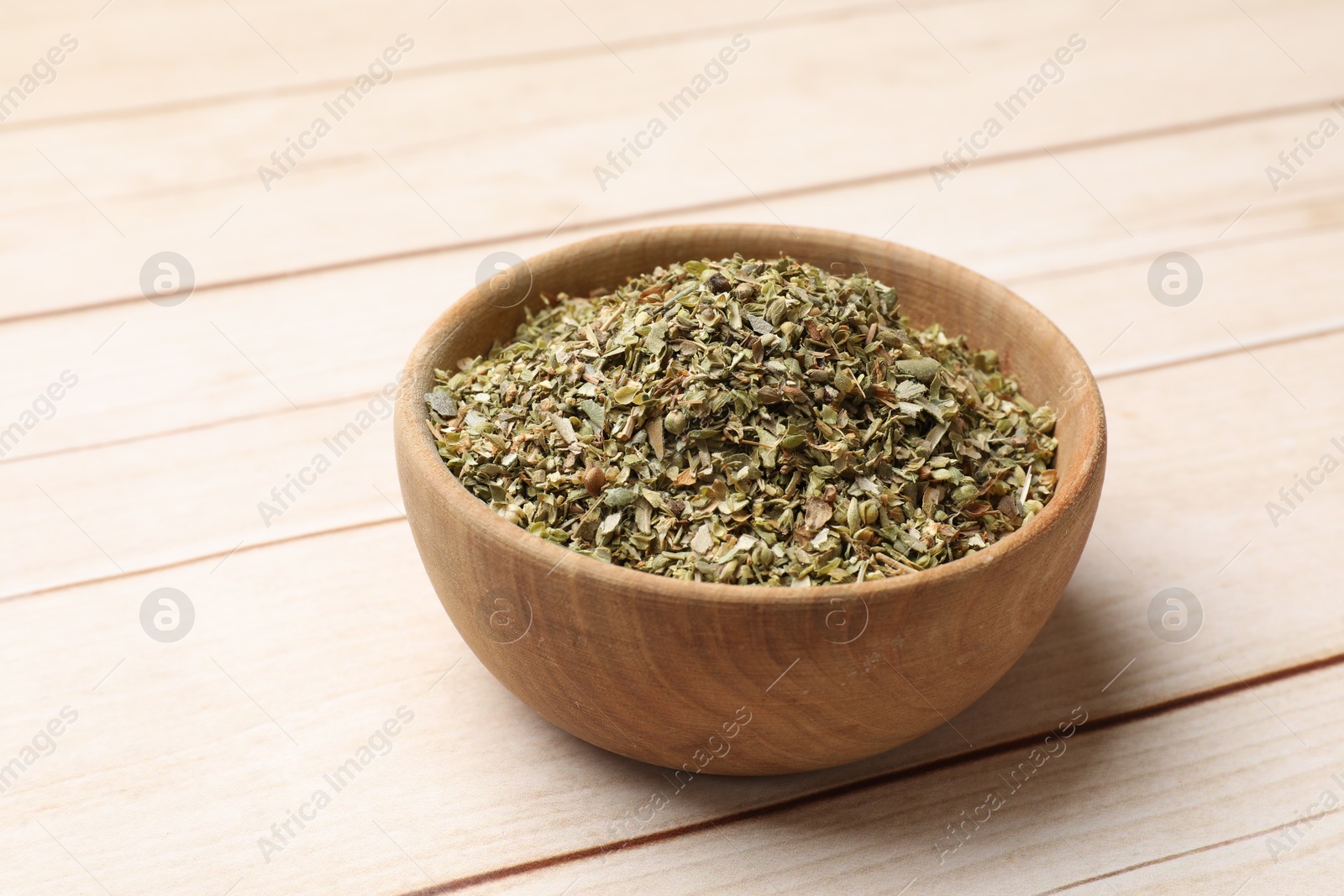 Photo of Dried oregano in bowl on wooden table, closeup