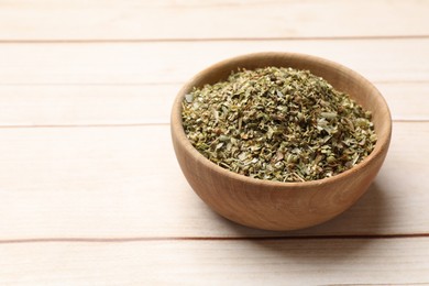 Photo of Dried oregano in bowl on wooden table, closeup. Space for text