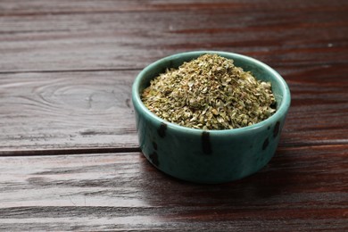 Dried oregano in bowl on wooden table, closeup. Space for text