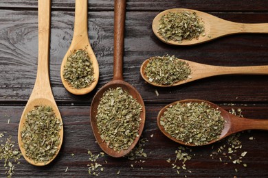 Dried oregano in spoons on wooden table, flat lay