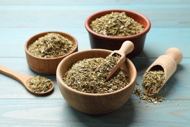 Photo of Dried oregano in bowls, scoops and spoon on light blue wooden table