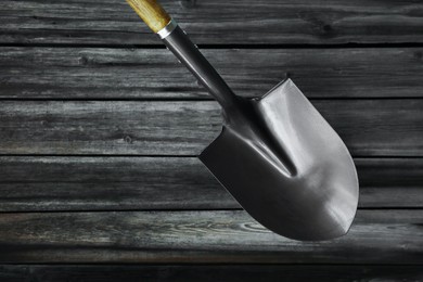 Photo of Metal shovel on black wooden surface, top view