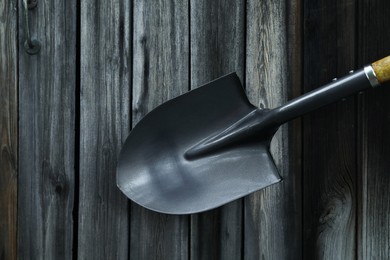 Photo of Metal shovel on black wooden surface, top view