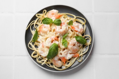 Photo of Tasty pasta with shrimps on white tiled table, top view