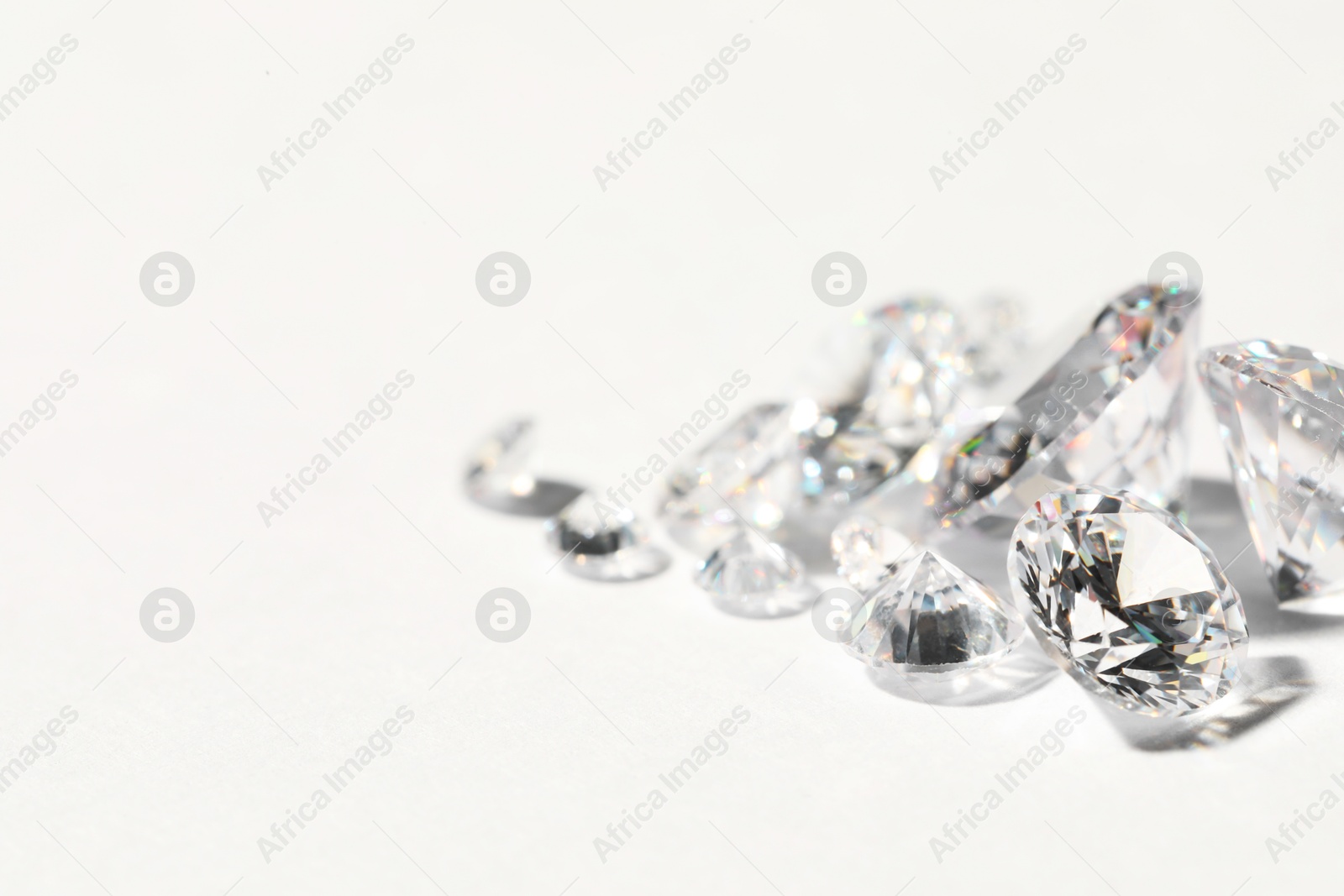 Photo of Many beautiful shiny diamonds on white background, closeup. Space for text