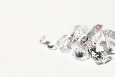 Many beautiful shiny diamonds on white background, closeup. Space for text