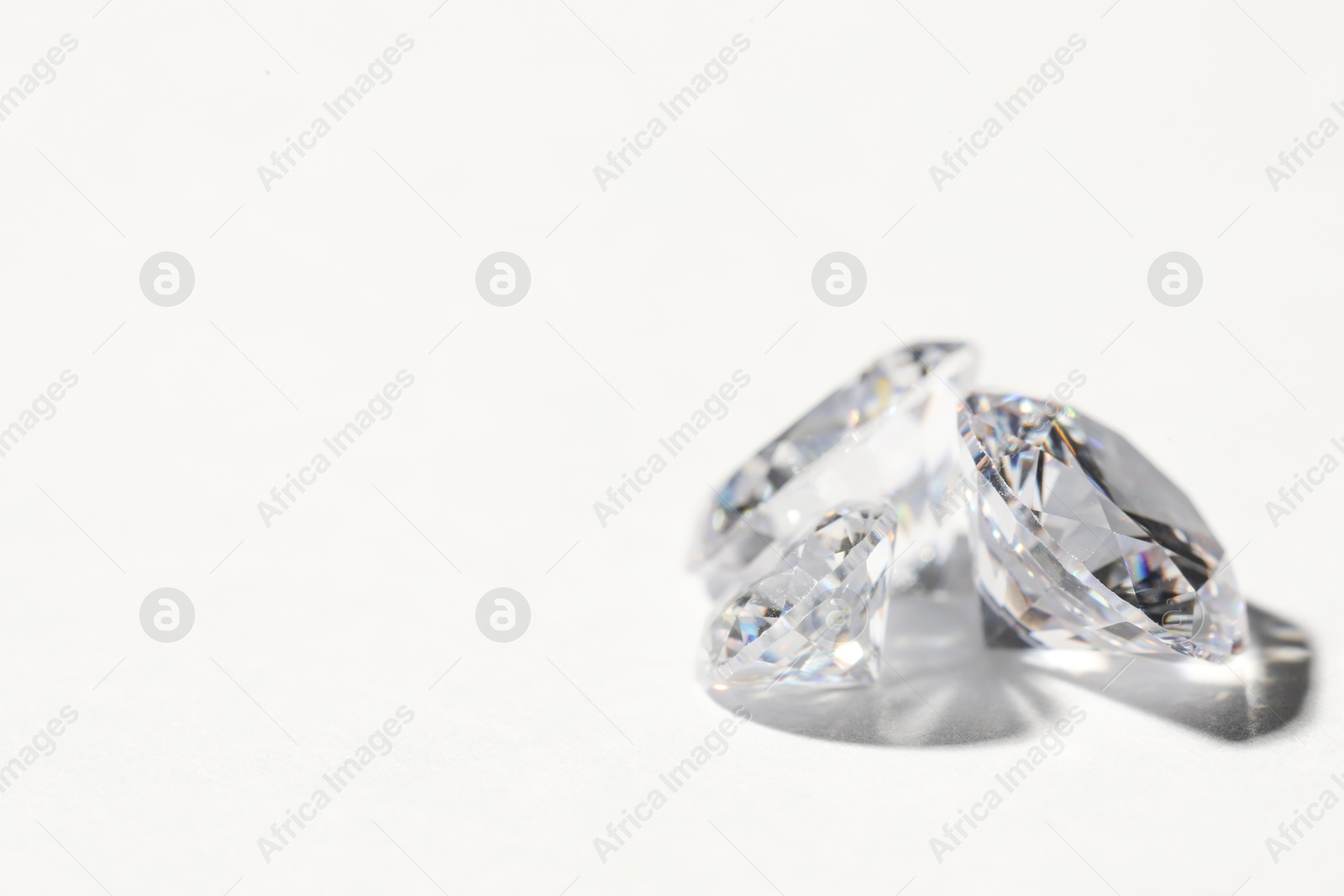 Photo of Two beautiful shiny diamonds on white background, closeup. Space for text