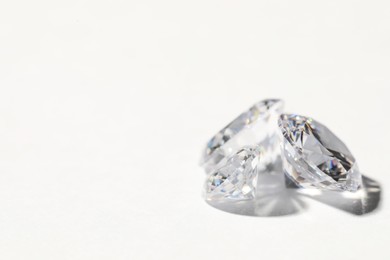 Photo of Two beautiful shiny diamonds on white background, closeup. Space for text