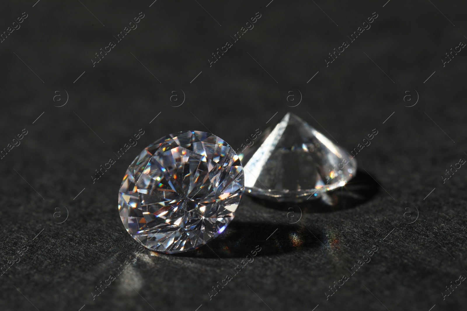 Photo of Two beautiful shiny diamond on black table, closeup