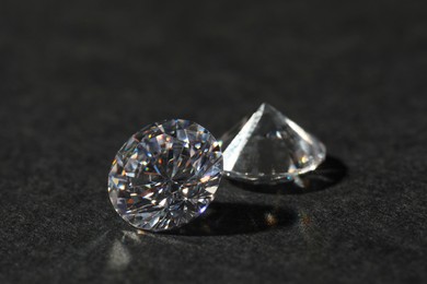 Photo of Two beautiful shiny diamond on black table, closeup