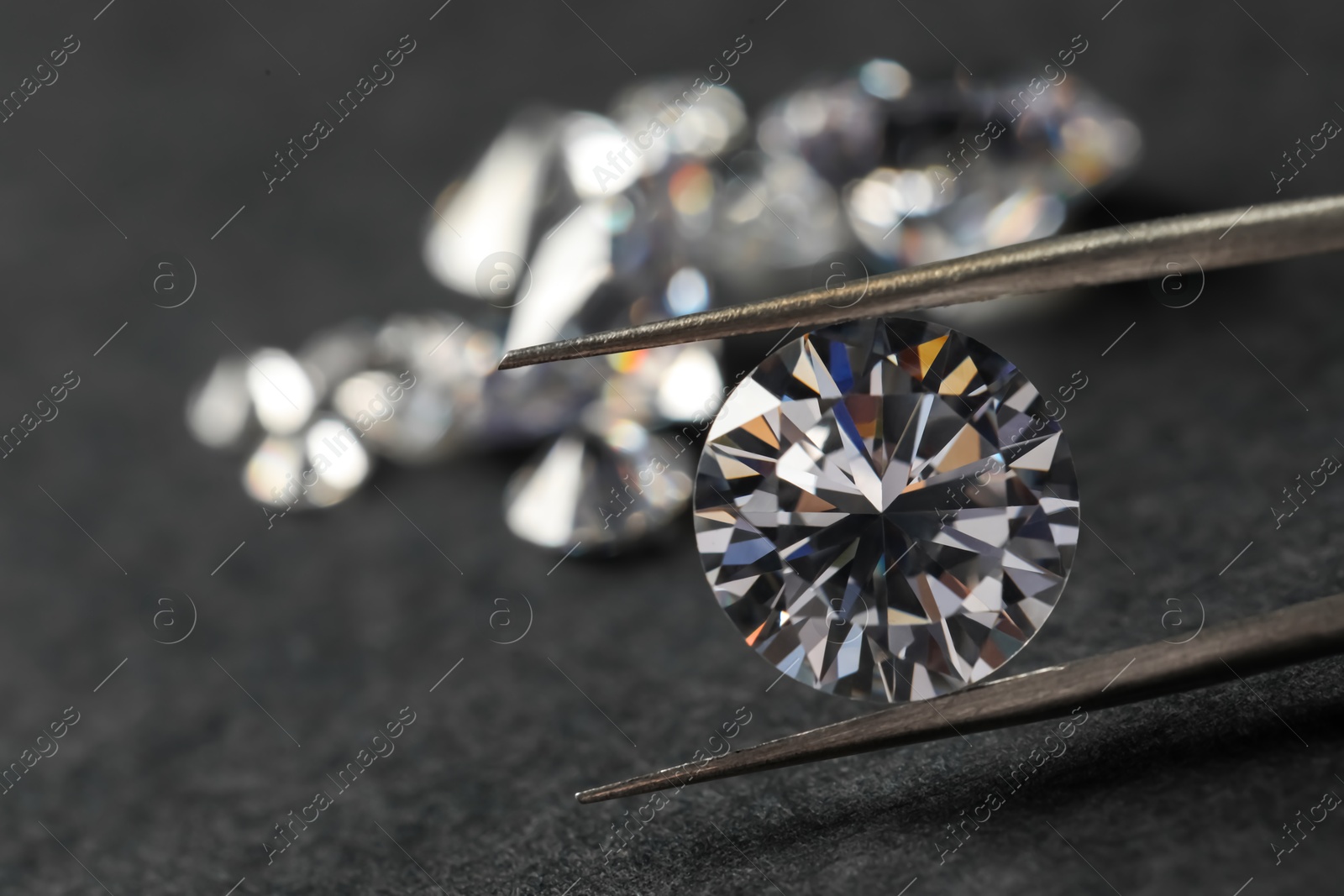 Photo of Many beautiful shiny diamonds and tweezers on black table, closeup