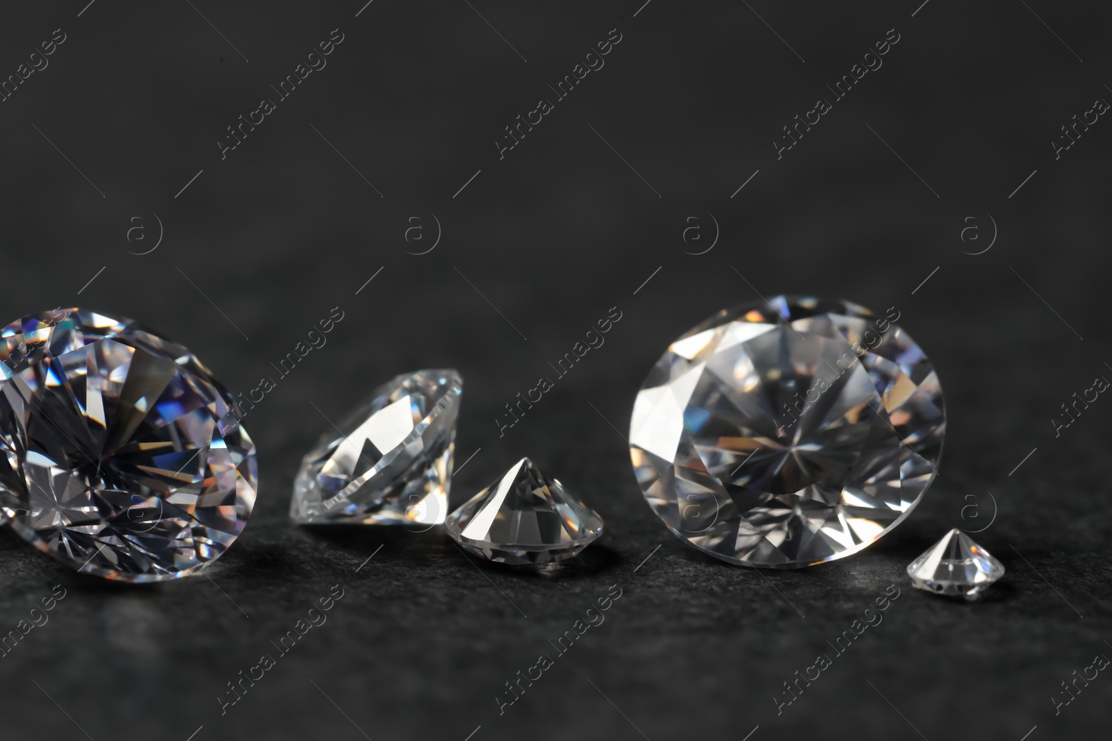 Photo of Many beautiful shiny diamonds on black table, closeup