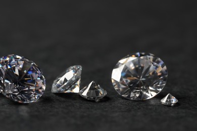 Many beautiful shiny diamonds on black table, closeup