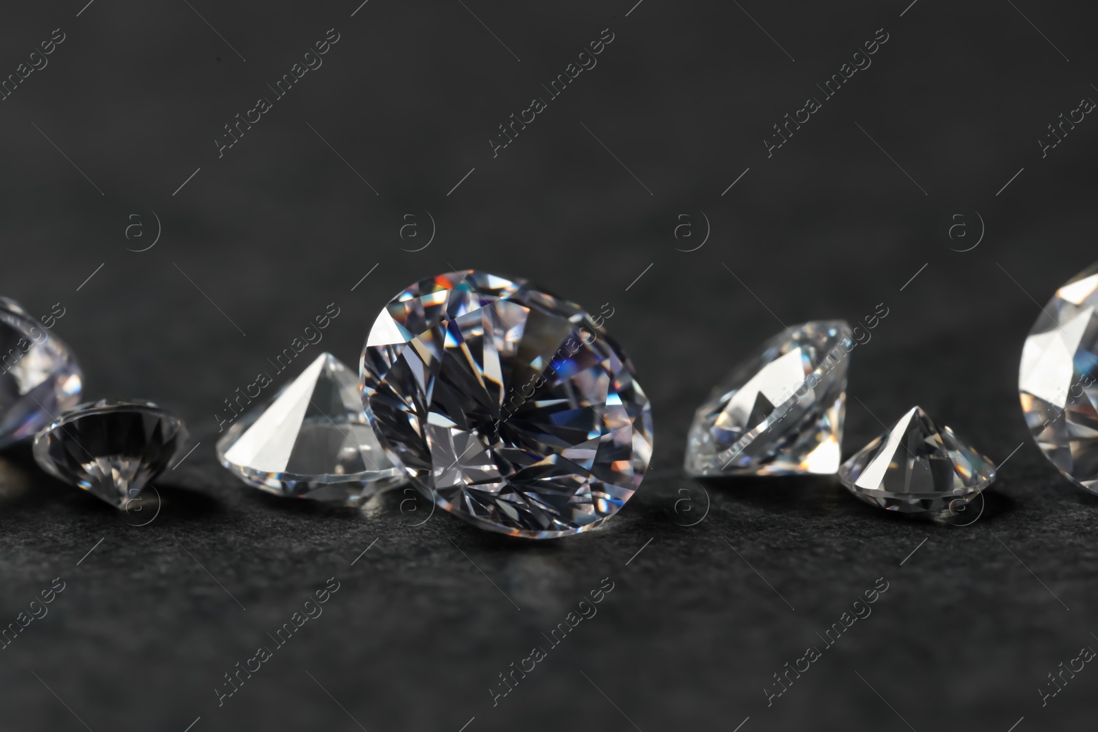 Photo of Many beautiful shiny diamonds on black table, closeup