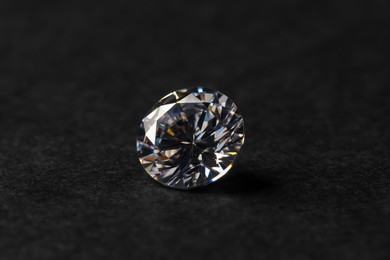 Photo of Beautiful shiny diamond on black table, closeup