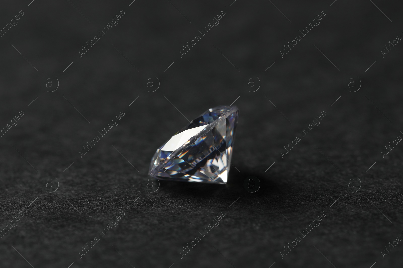 Photo of Beautiful shiny diamond on black table, closeup