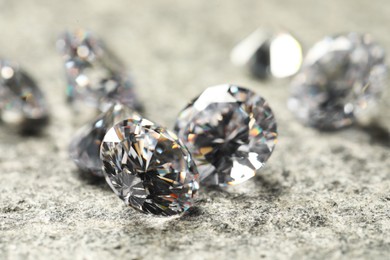 Many beautiful shiny diamonds on grey table, closeup