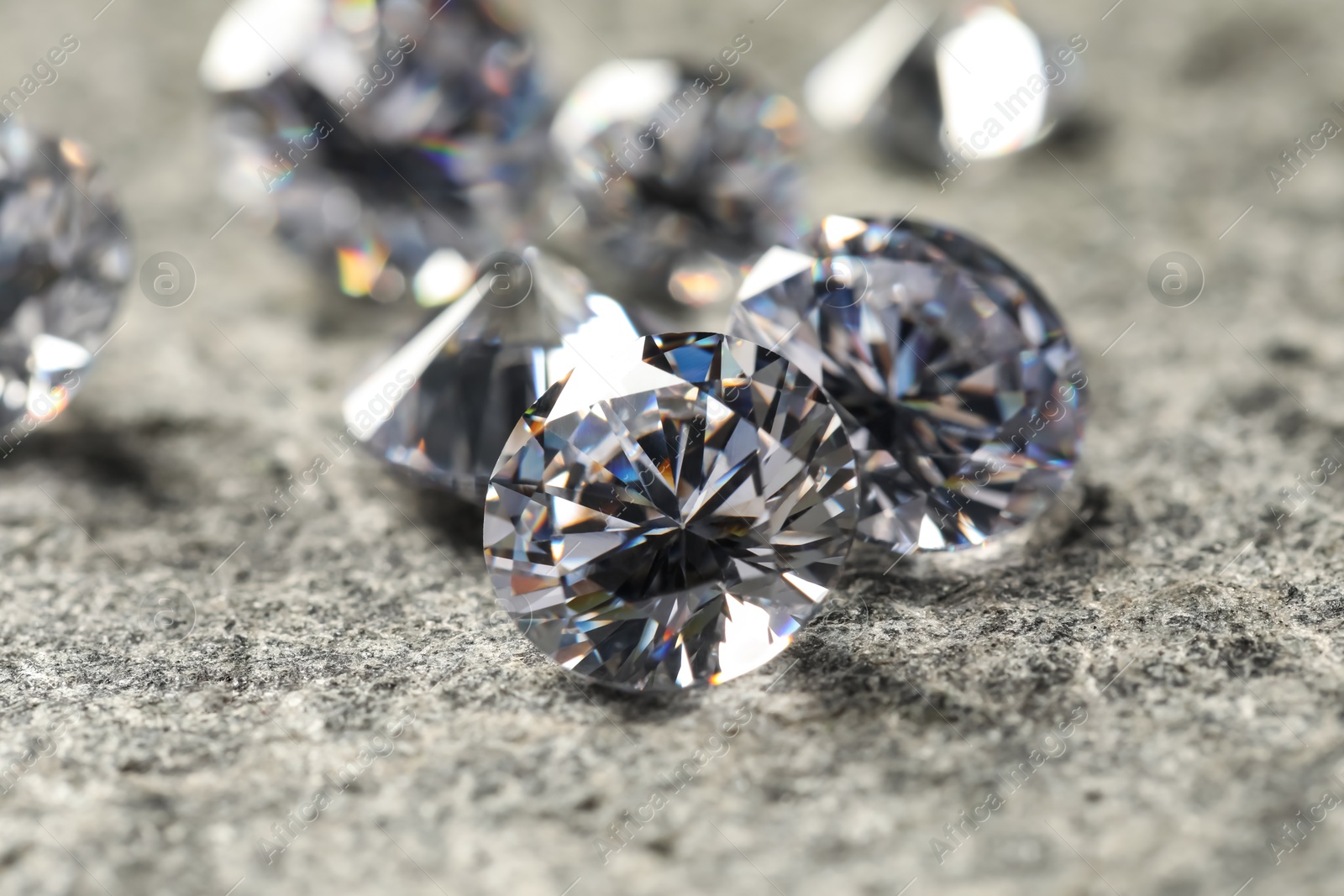 Photo of Many beautiful shiny diamonds on grey table, closeup