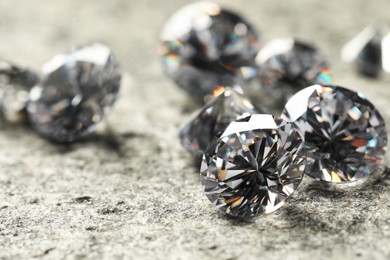 Many beautiful shiny diamonds on grey table, closeup