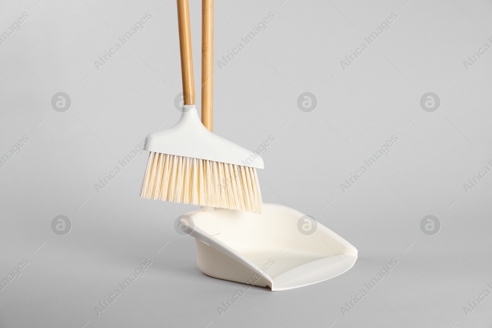 Photo of Cleaning broom and dustpan on grey background