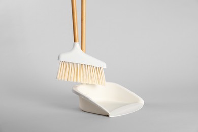 Photo of Cleaning broom and dustpan on grey background