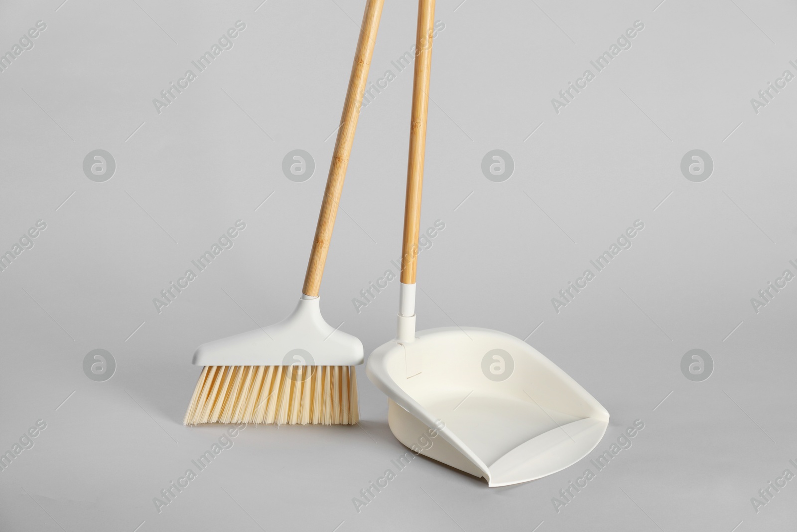 Photo of Cleaning broom and dustpan on grey background