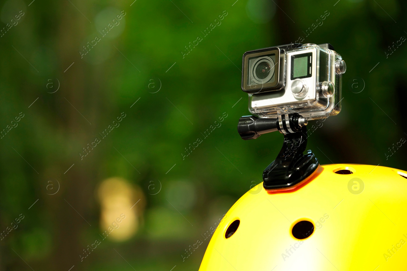 Photo of Modern action camera with mount on helmet outdoors, closeup. Space for text