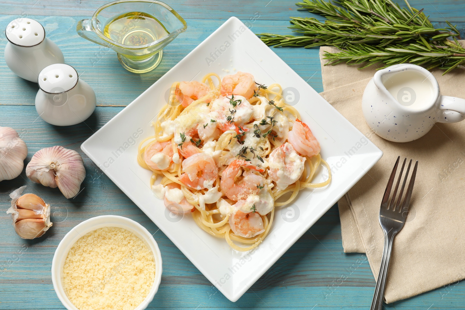 Photo of Delicious pasta with shrimps served on blue wooden table, flat lay